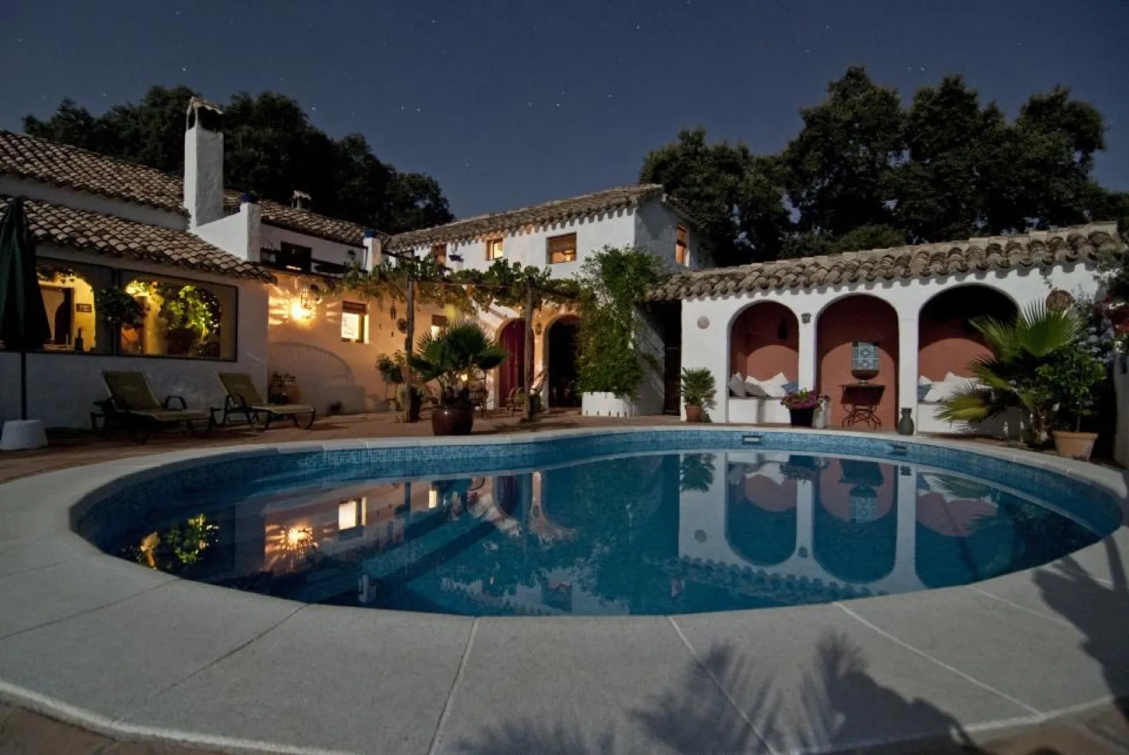 Villa andaluza con piscina iluminada al anochecer