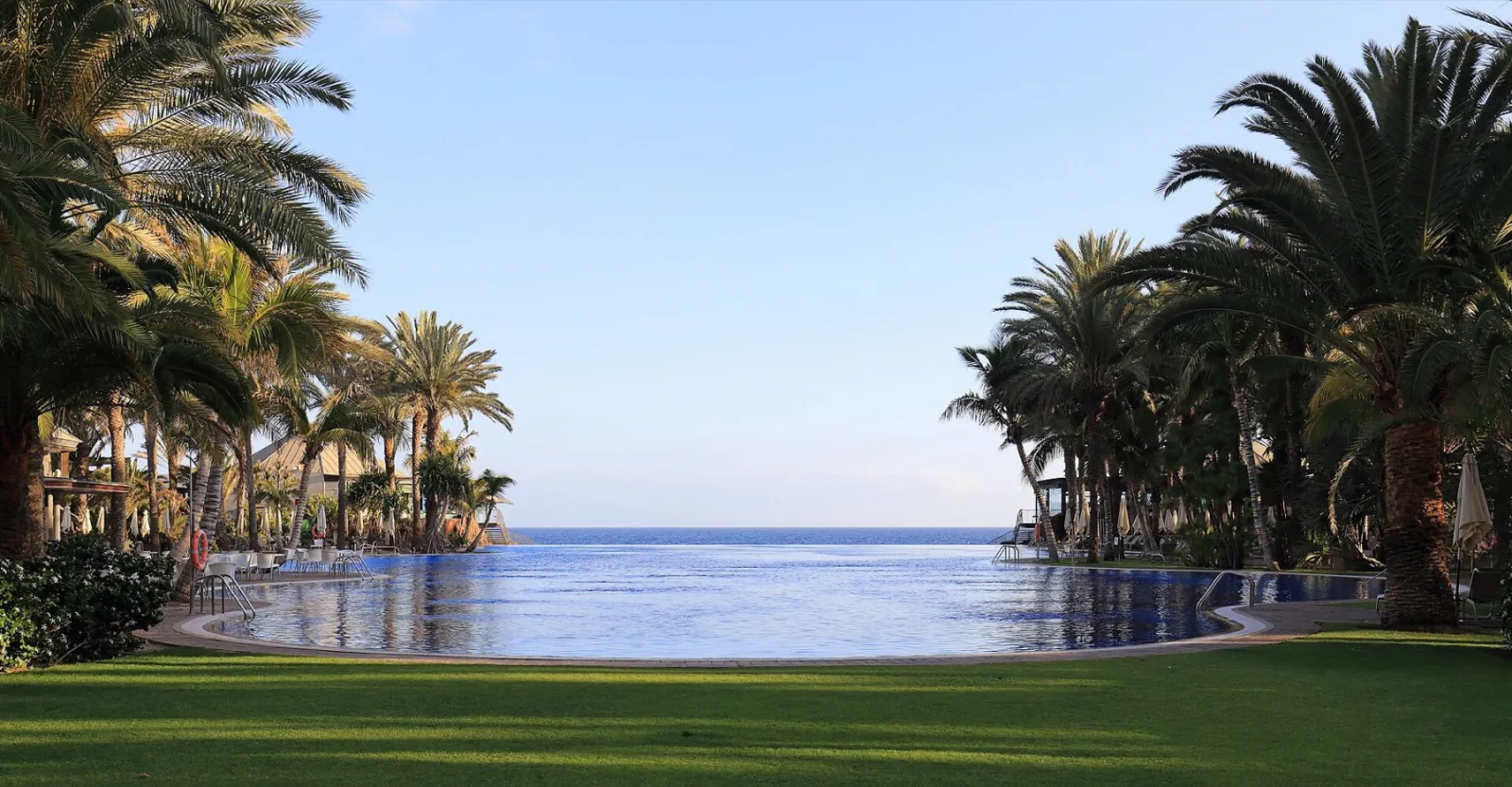 Piscina infinita entre palmeras con vistas al mar