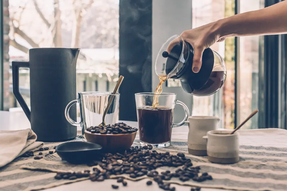 Café de filtro servido en vasos sobre una mesa con granos
