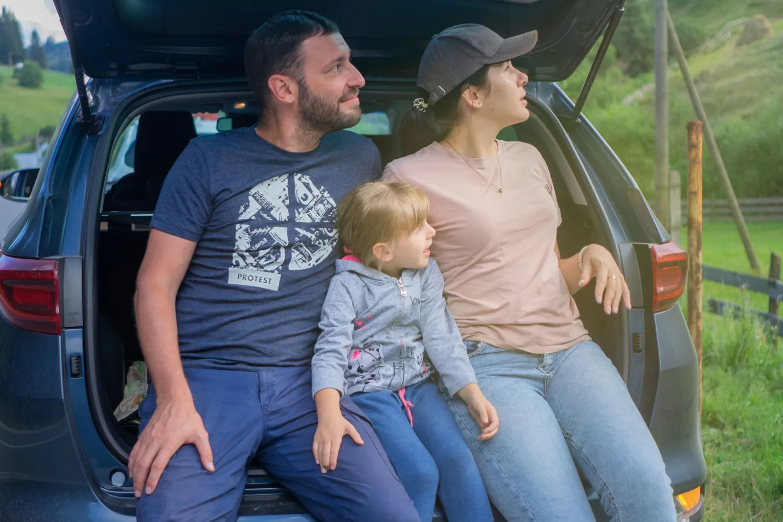 Familia sentada en el maletero de su coche durante una excursión
